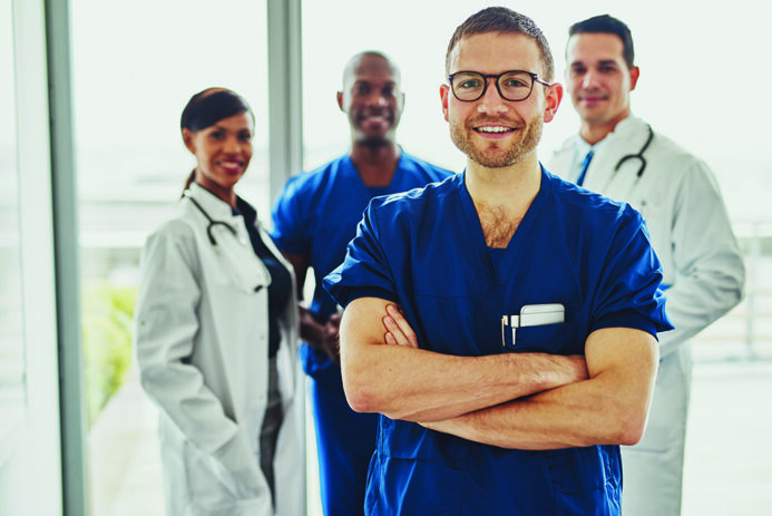 Confident doctor in front of group smiling at the camera, wearing surgeon clothes