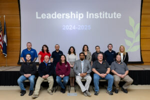 A group of participants poses together on stage in front of a large screen that reads “Leadership Institute 2024–2025” at Laurel Ridge Community College.