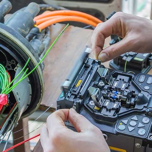 a close up image of a worker's hands checking on fiber optic cables