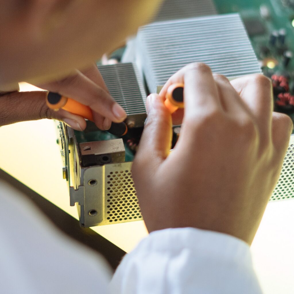 Data Center Technician two hands use small tools to work on a circuit board